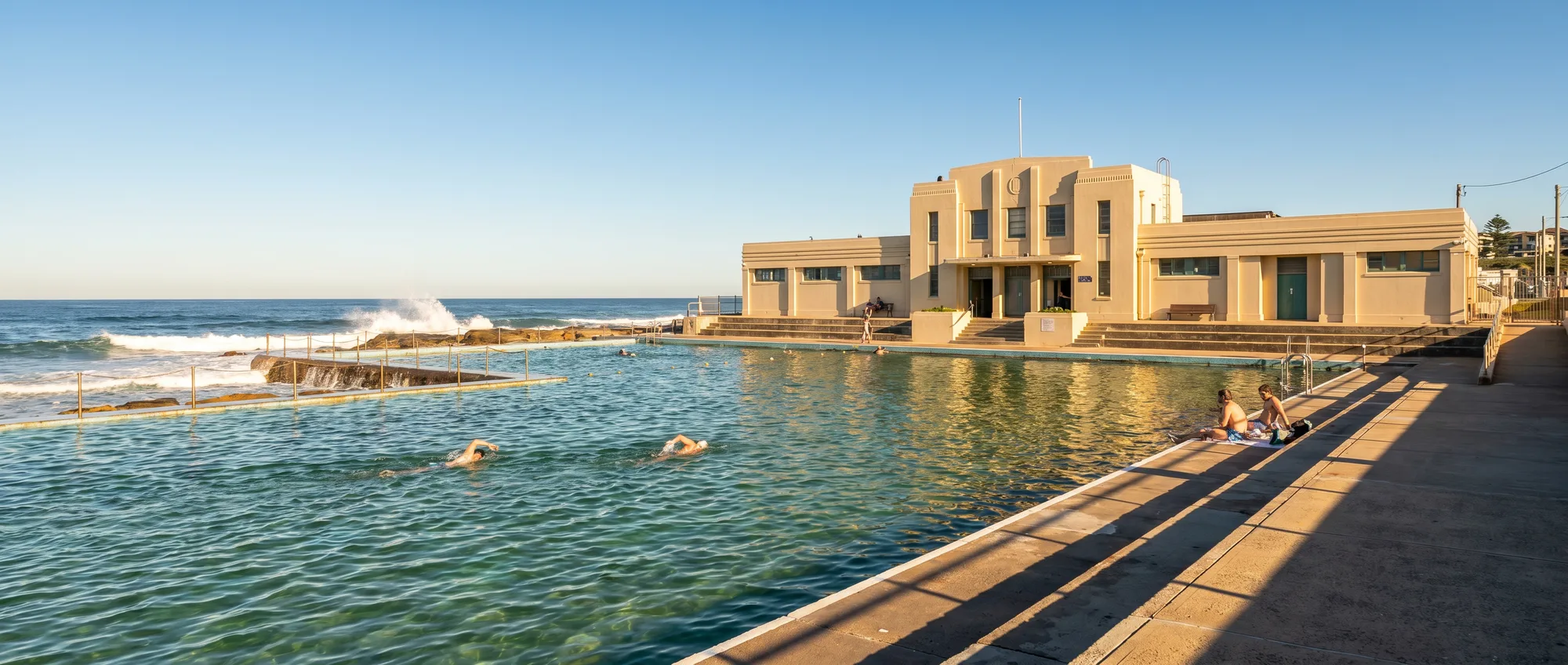 Newcastle Ocean Baths in morning light, swimmers in the green pool